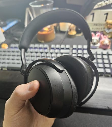 a hand holding headphones in front of a keyboard